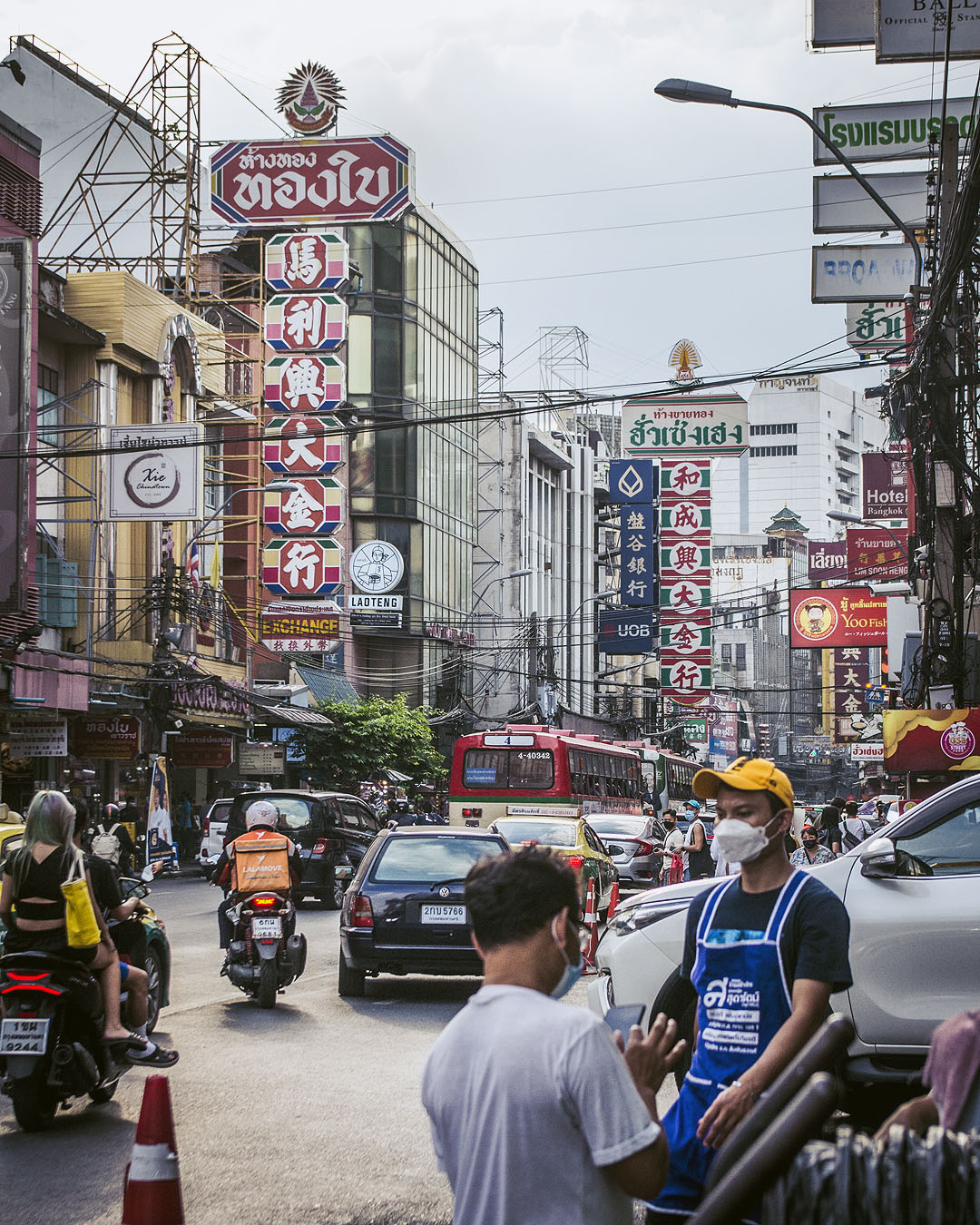 Store signs, vendors, cars and buses on Yaoworat Road in Bangkok's Chinatown.