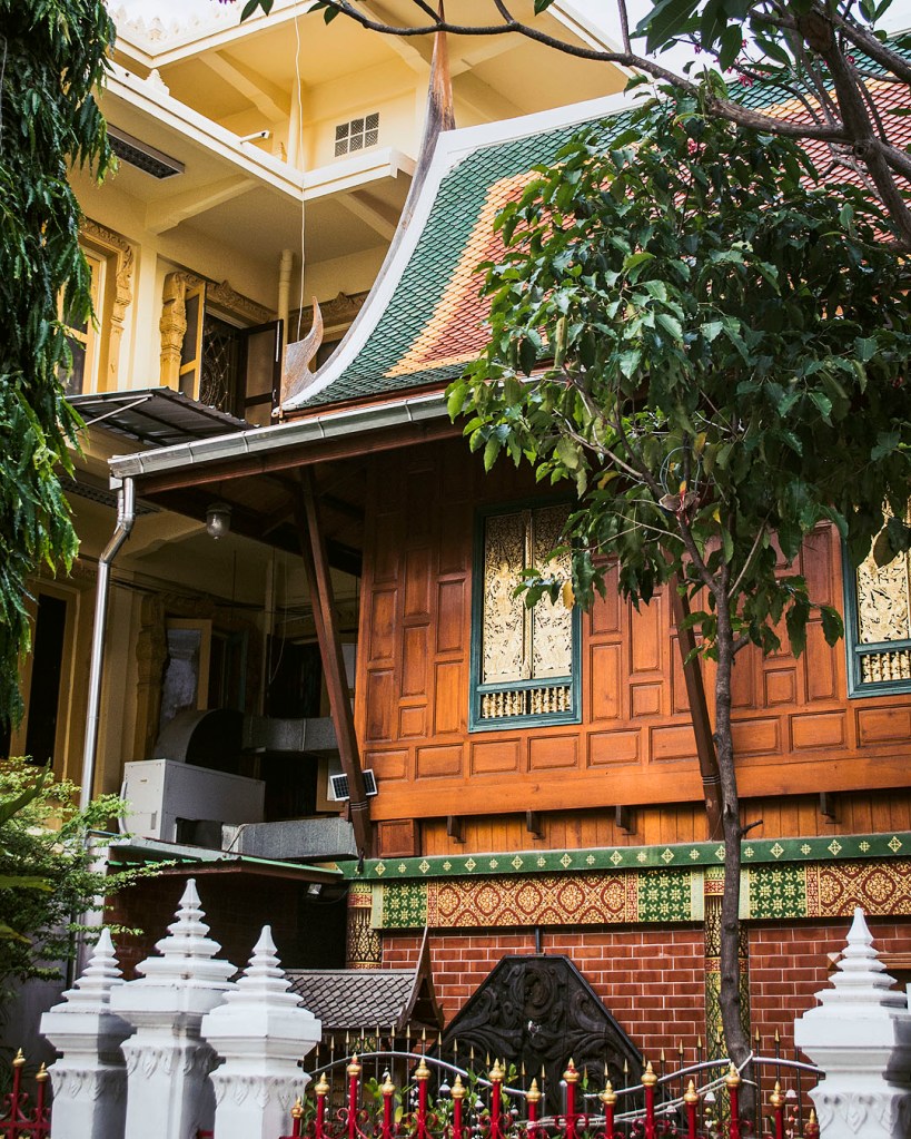 A building with a green and red roof in the grounds of Wat Samphanthawong.