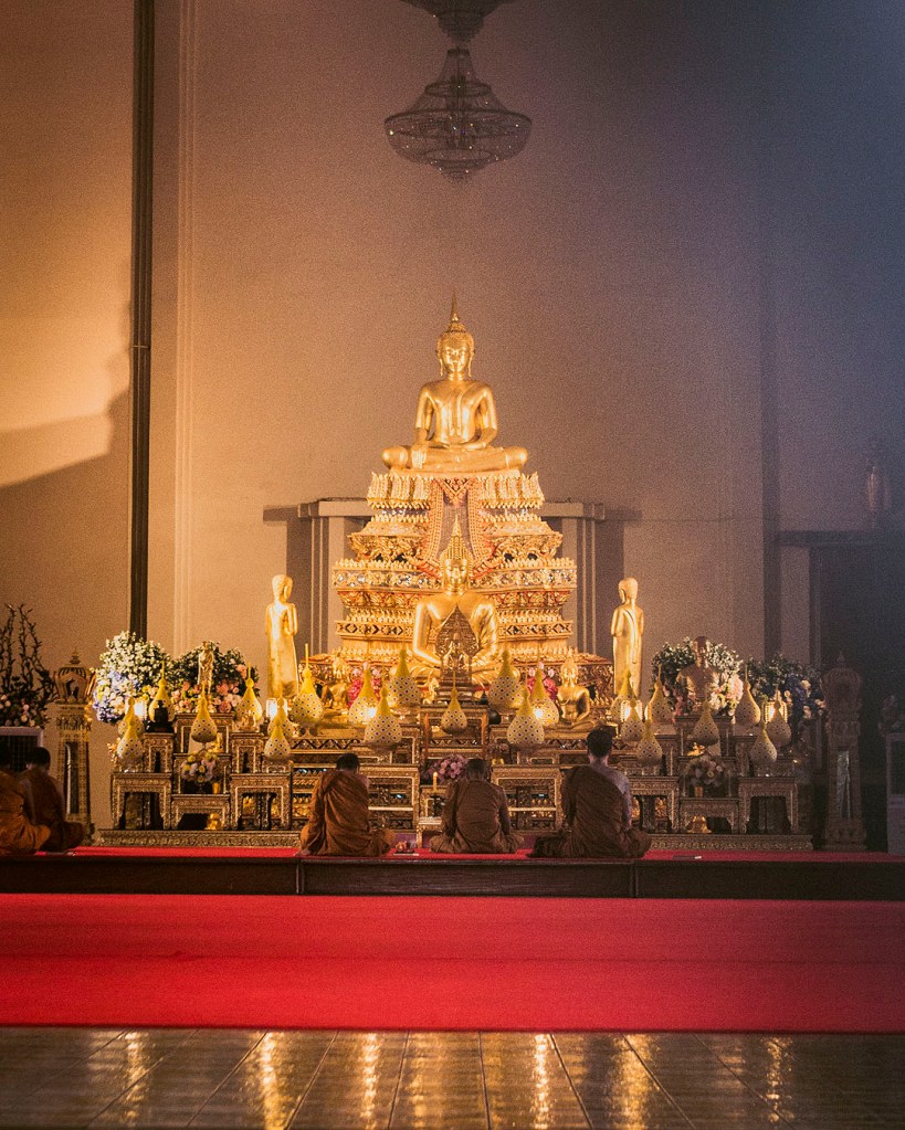 Buddhist monks chanting in front of a golden Buddha image at Wat Samphanthawong (Wat Ko) in Bangkok.