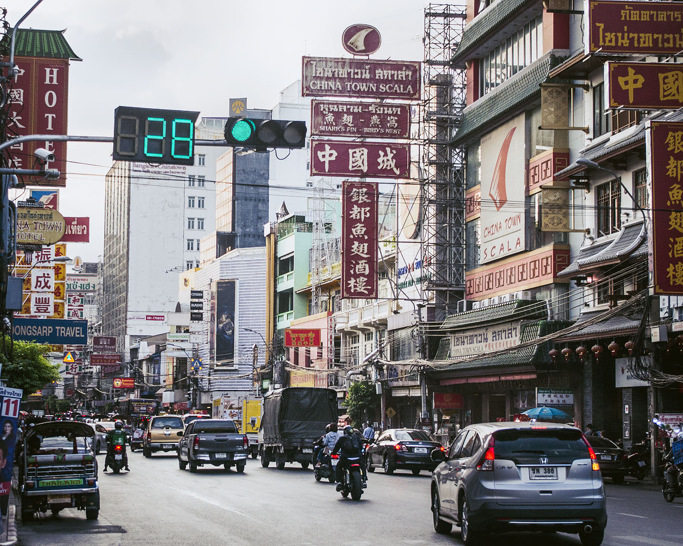 Store signs, motorbikes and cars on Yaoworat Road in Bangkok's Chinatown.