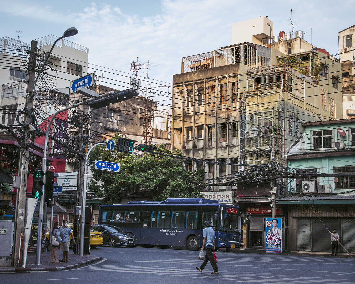 A man crossing a road in front of a bus in Bangkok's Chinatown.