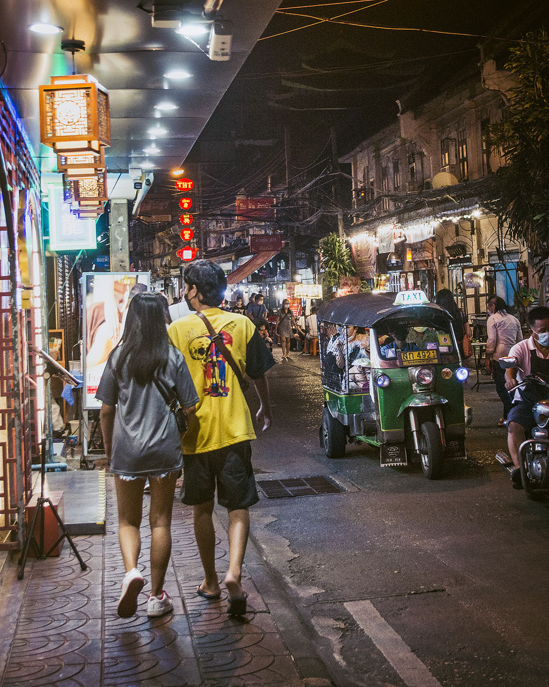 Pedestrians and a tuktuk in an alleyway in Bangkok's Chinatown.