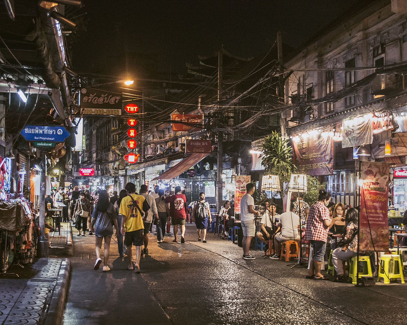 An alleyway filled with stalls and pedestrians in Bangkok's Chinatown.