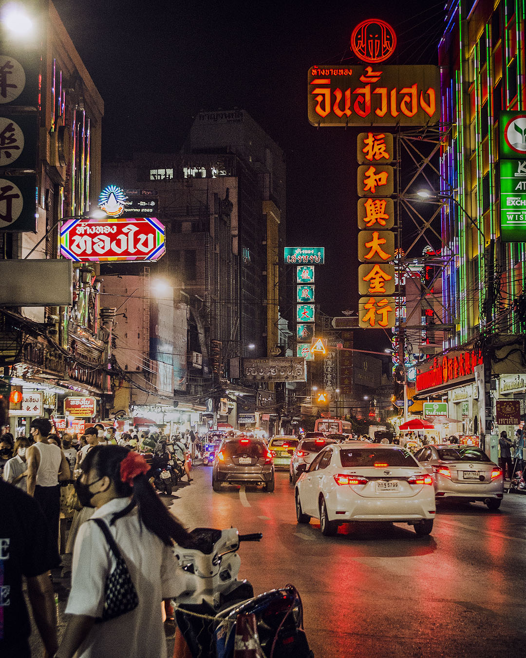 Colourful neon signs, cars and pedestrians on Yaoworat Road at night.