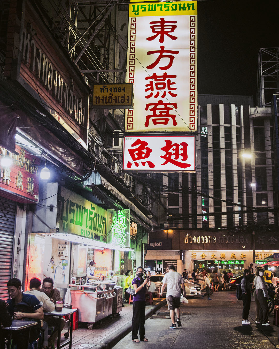 Street food in an alleyway in Bangkok's Chinatown at night.
