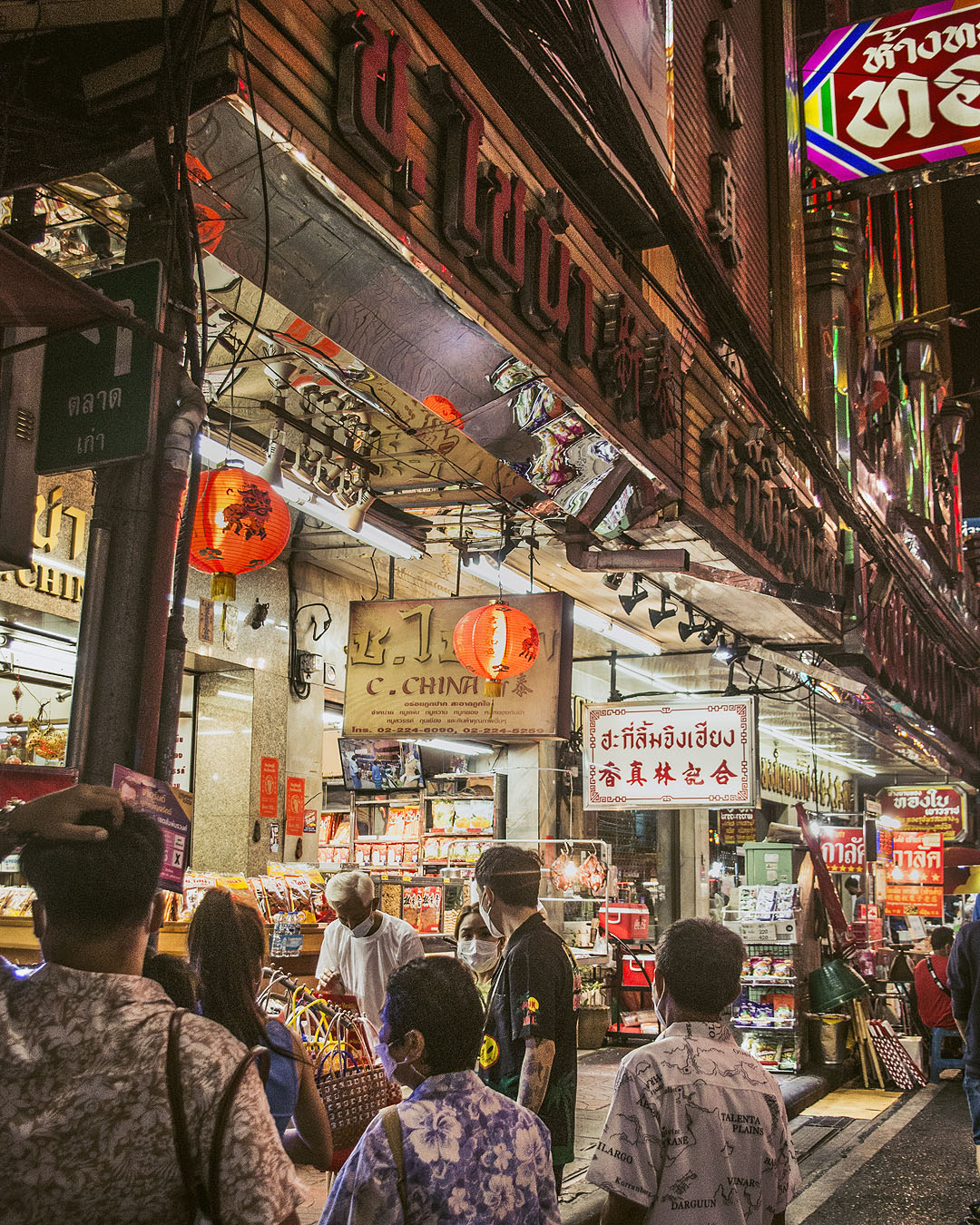 Pedestrians outside shops on Yaoworat Road at night.