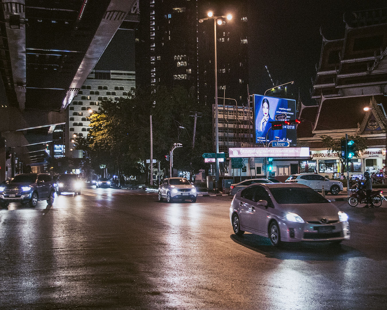 Headlights reflected on a road in Bangkok at night.