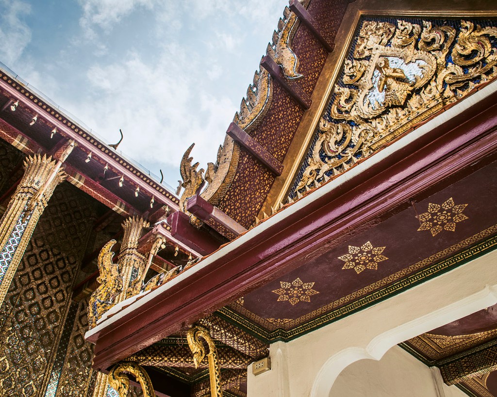 Intricate golden details on roofs and columns at the Grand Palace in Bangkok.