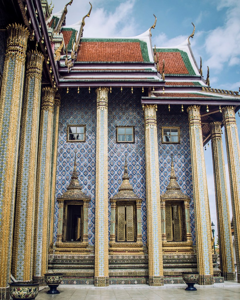 Blue mosaic walls, colums and red-and-green tiled roofs of the Royal Pantheon in the Grand Palace complex in Bangkok, Thailand.