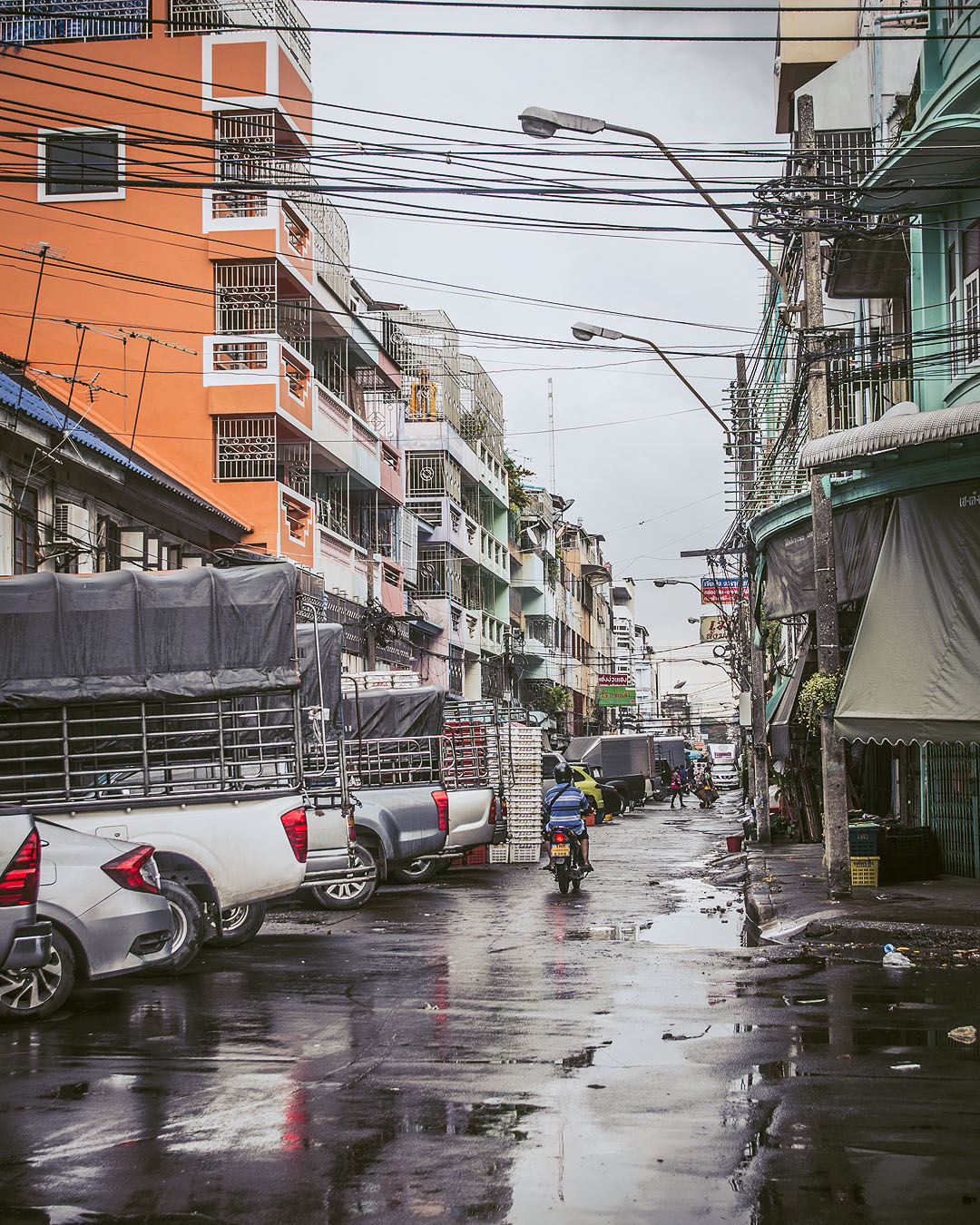 Colourful houses and parked cars in an alleyway in Bangkok.