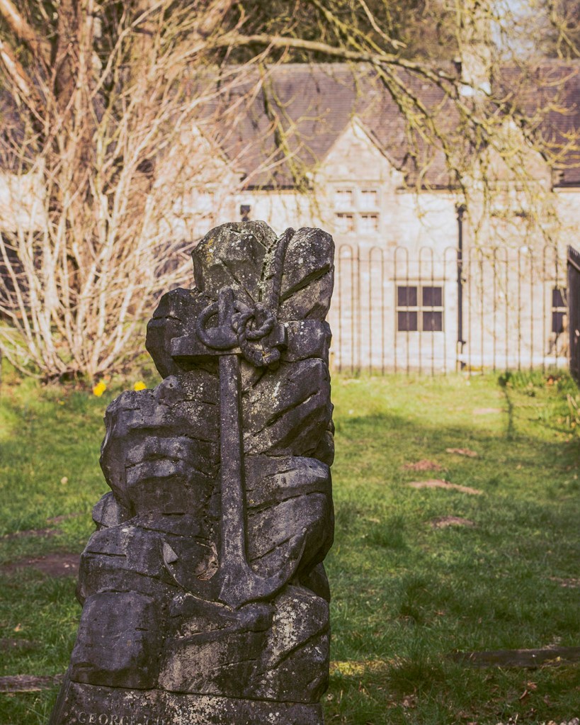 An anchor-themed headstone in front of the remains of Annesley Lodge, at Annesley Old Church in Nottinghamshire.