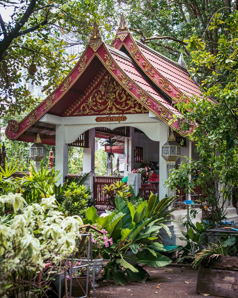 A red-roofed pavilion in the grounds of Wat Muen San, surrounded by greenery.