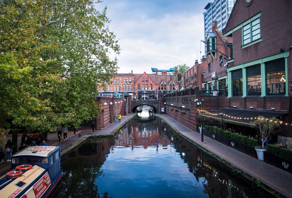 Red-brick buildings and a blue sky reflected in Birmingham Canal.