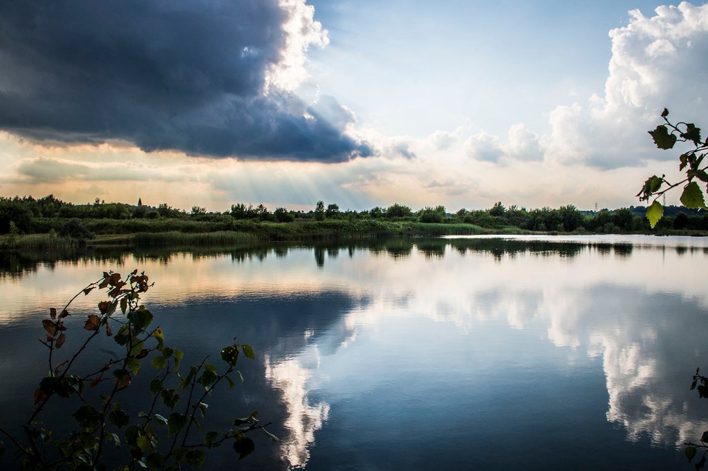 A blue sky and clouds reflected in a clear lake at Newstead and Annesley Country Park.