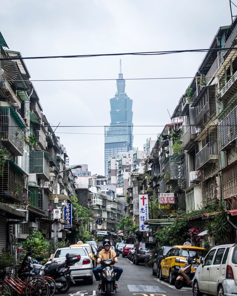 A street in Taipei. Taipei 101 is framed by apartment blocks on a narrow street.