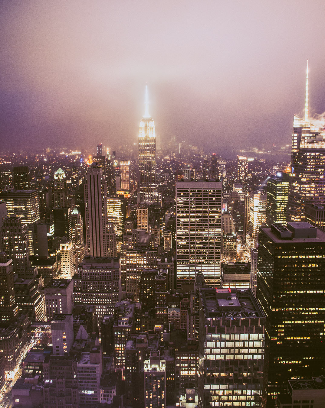 The illuminated skyline of New York City, dominated by the Empire State Building, viewed from Top of the Rock.