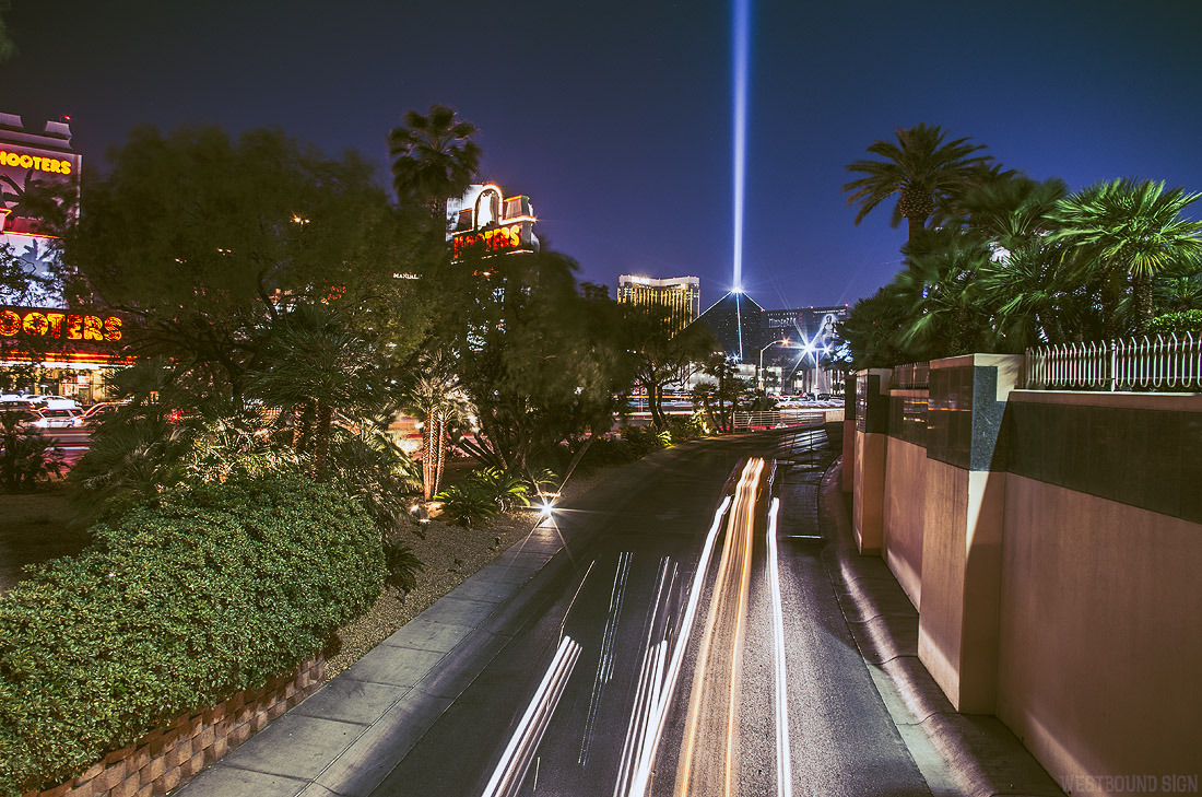 Light trails on a road and the lights of the Las Vegas skyline in the distance.